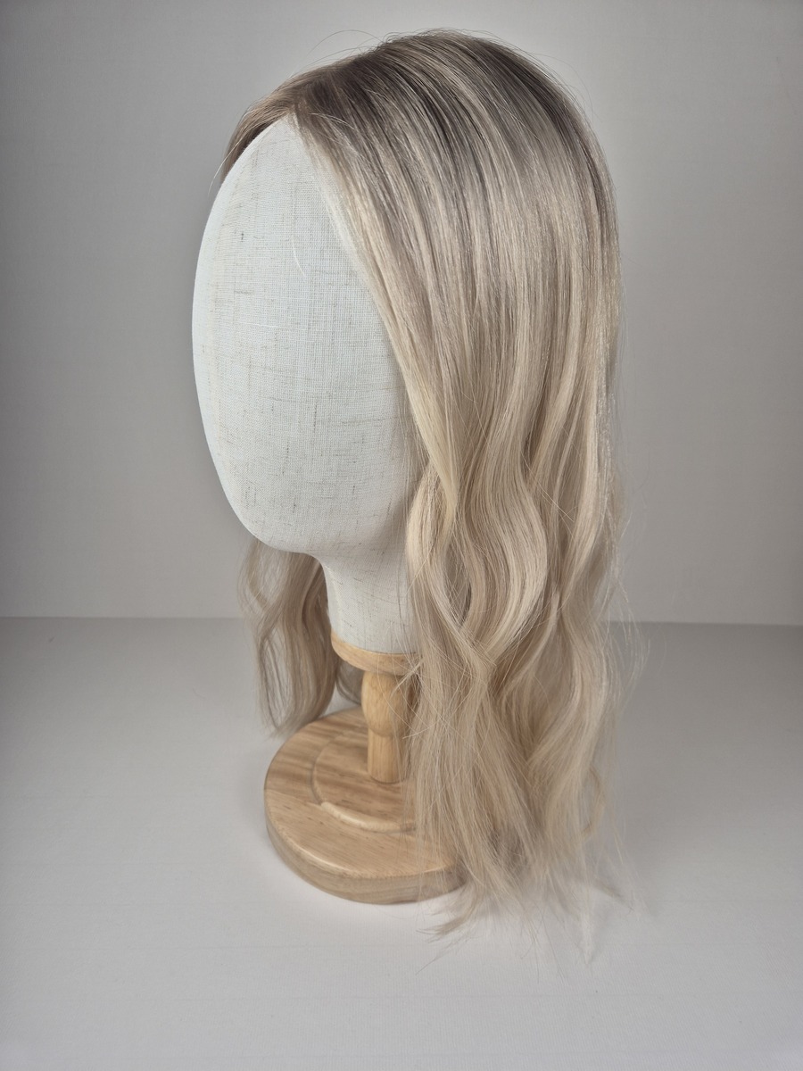 Claire Ribbon Silk l topper 18 inches in length light blonde with a beige root styled wavy displayed on a Mannequin