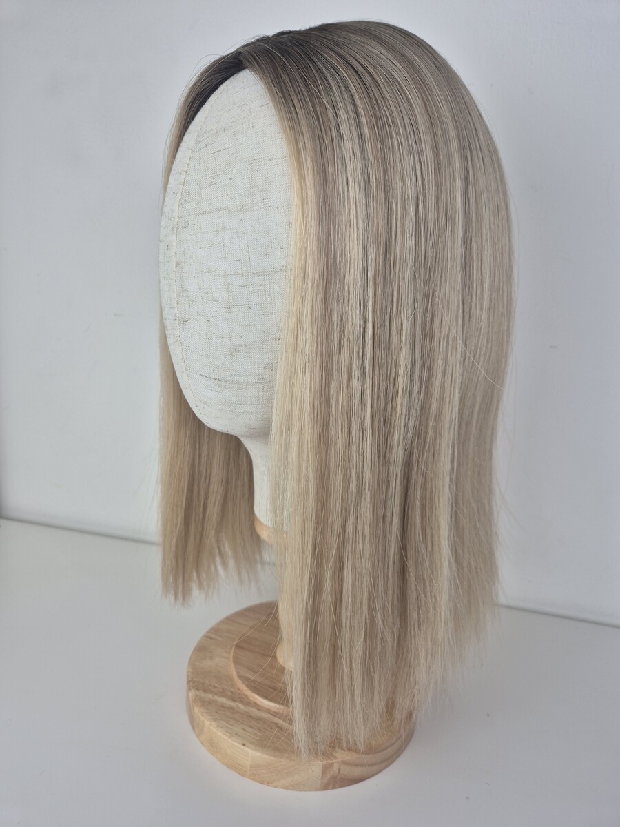 Clara silk topper warm neutral blonde with darker root 16 inch styled straight and displayed on a mannequin