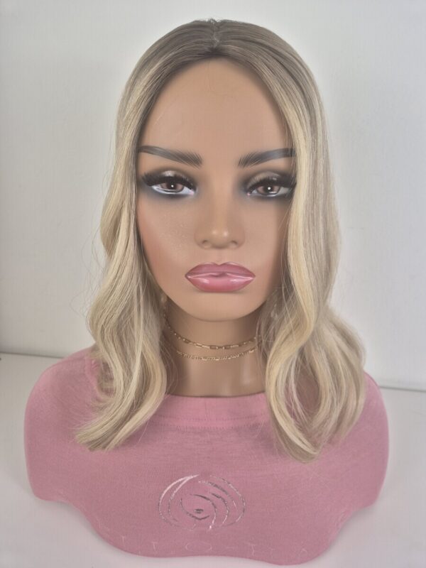 Clara silk top hair topper 16 inches in length. warm to neutral blonde with a level 7 root Displayed on a mannequin