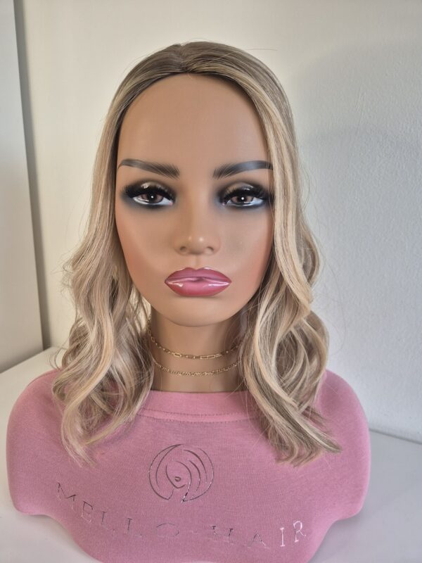 Lacie silk top hair topper 16 inches in length blonde with a darker root displayed on a mannequin