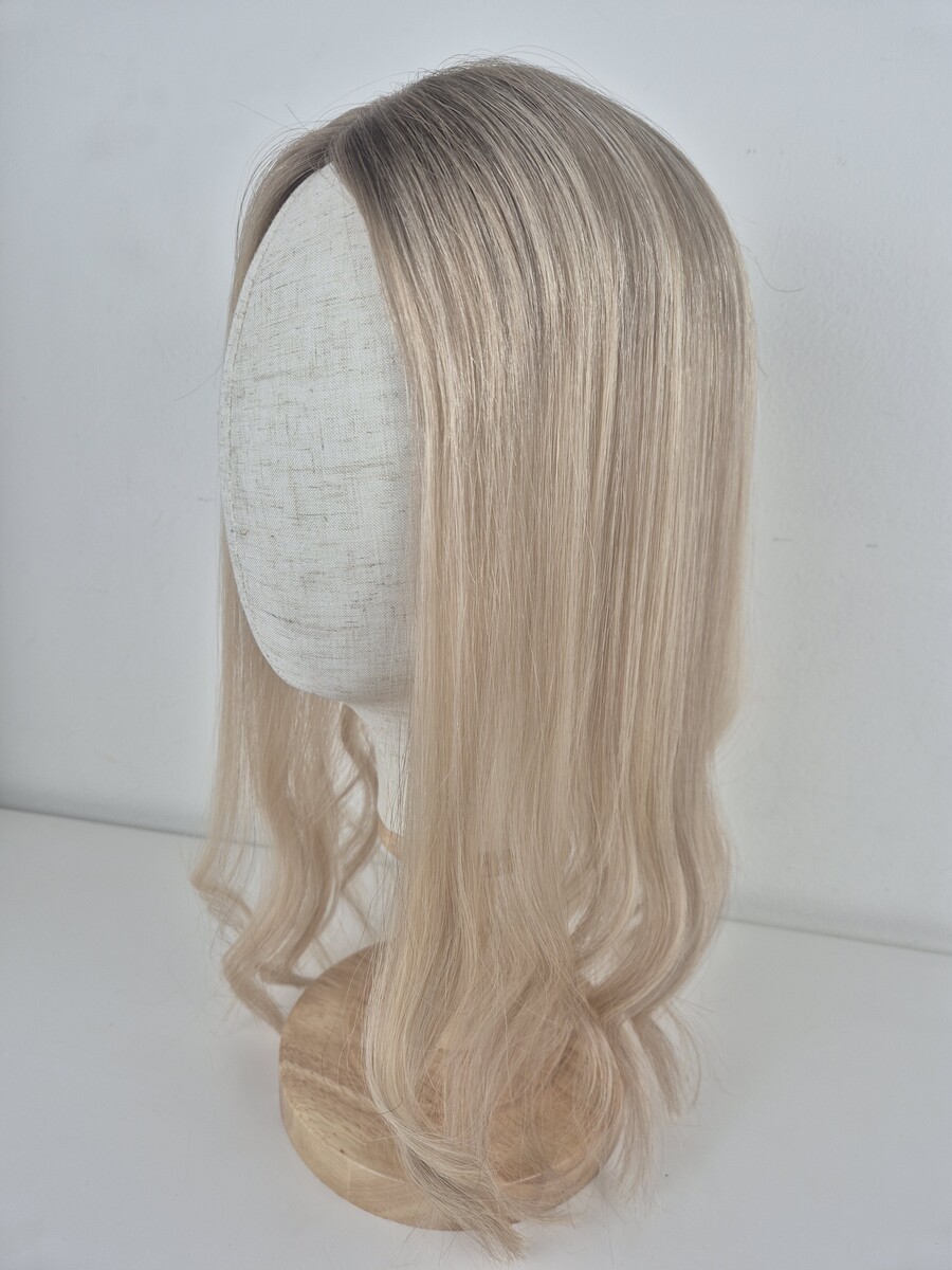 Tiny Topper Clara low-density hair topper 16-inch length styled straight neutral blonde with a subtle ash root melt. styled with a wave displayed on a mannequin
