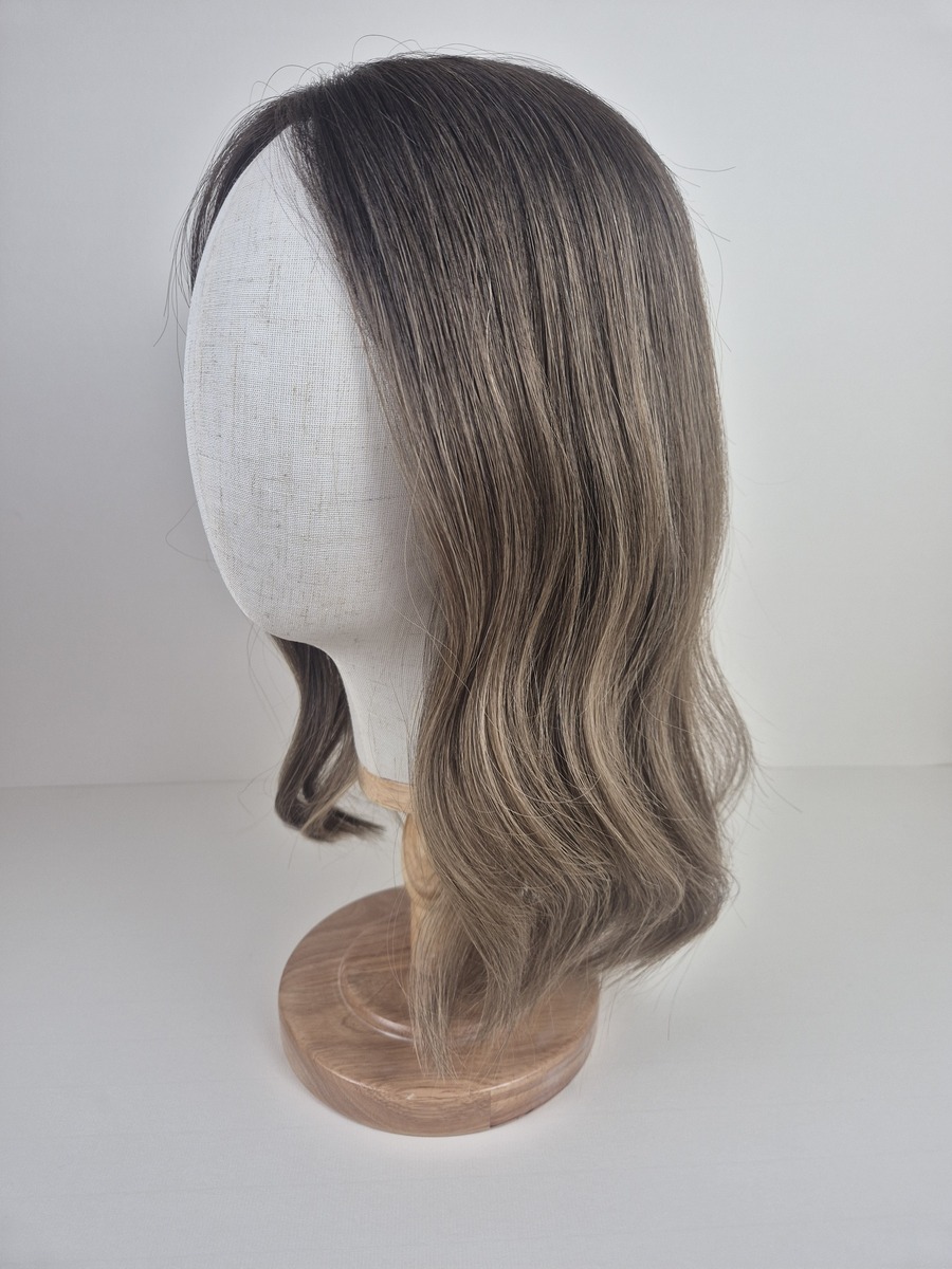 Lydia lace topper 16 inches medium brown root melting into a lighter ash beige brown. Displayed on a mannequin styled waved