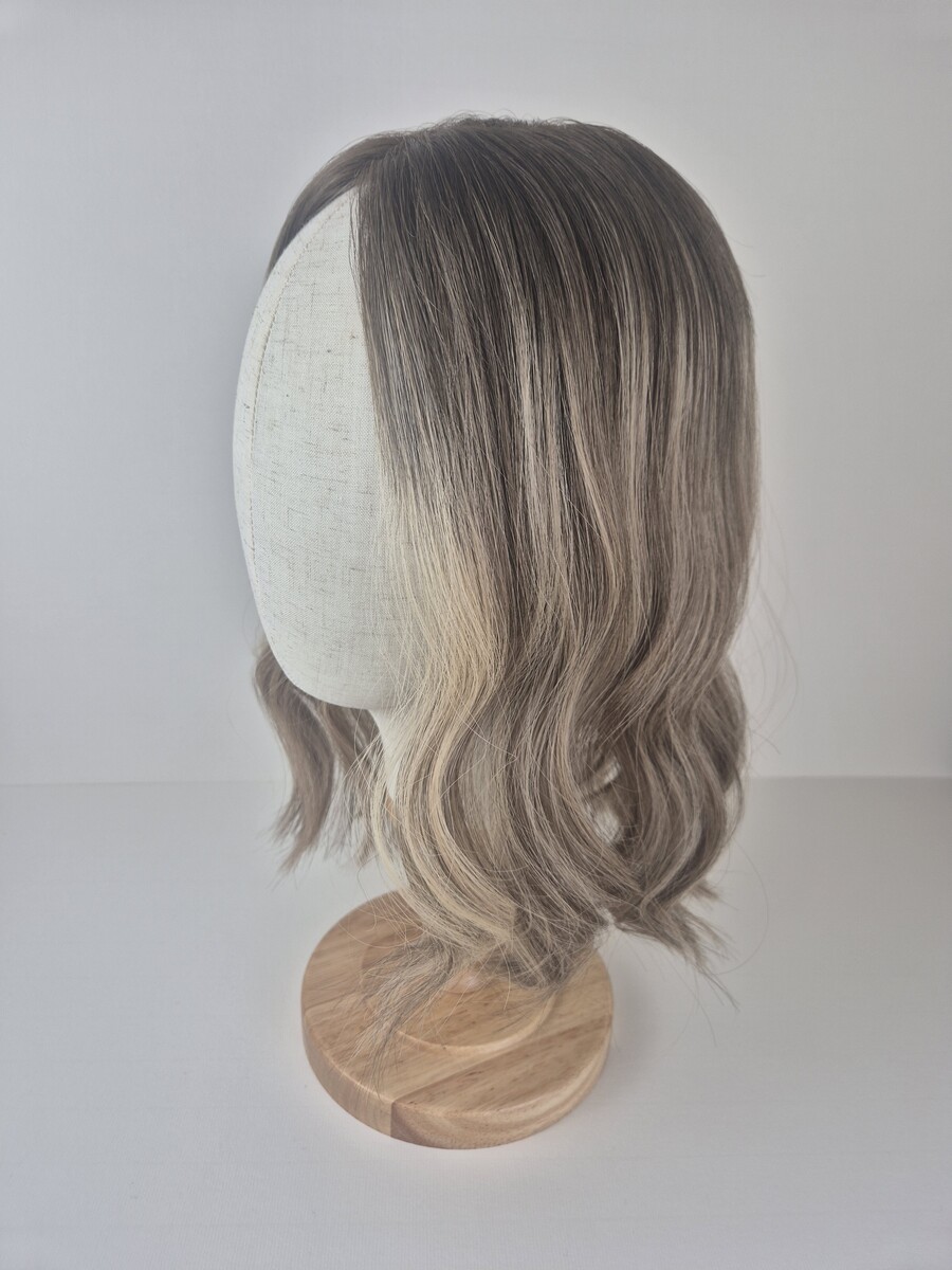 Ava 14 inch length beige blonde with a ash brown root 7x7 cap styled with a wave displayed on a mannequin head