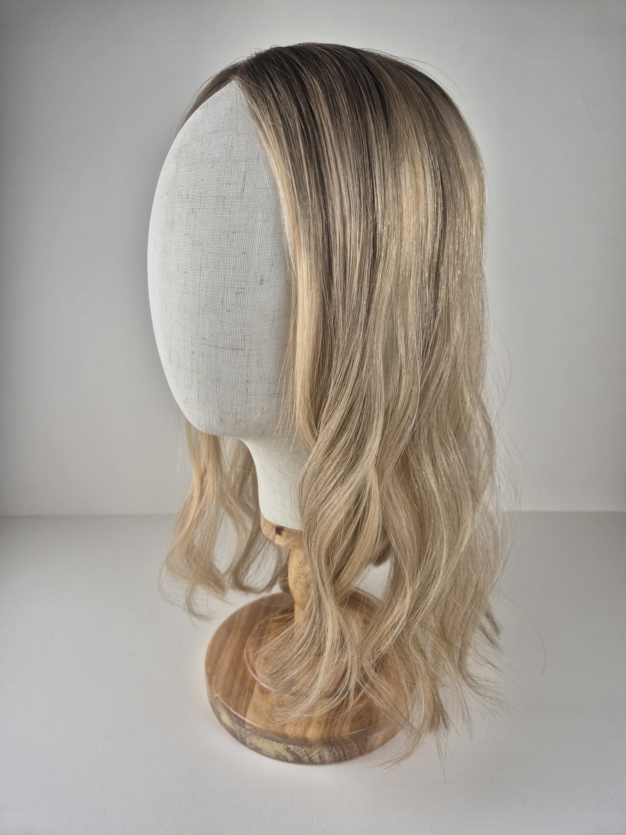 Kelly Little Lace topper 16 inches light blonde with a subtle dark root styled wavy displayed on a mannequin
